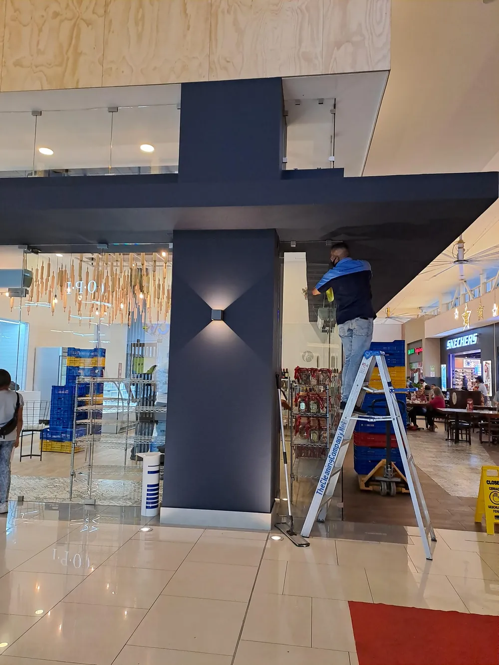 Técnico limpiando pared y luminaria en altura en un proyecto recién construido